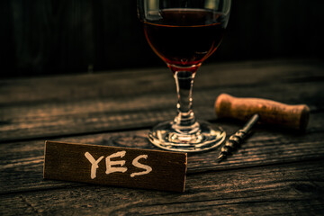 Glass of red wine with corkscrew and the wooden plank on it is an inscription 