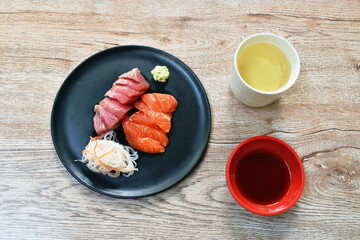 slice raw tuna and salmon fish sashimi Japanese food with radish on plate dipping shoyu  or soybean sauce couple wasabi 