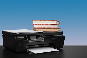 Compact laser printer on black desk against blue background