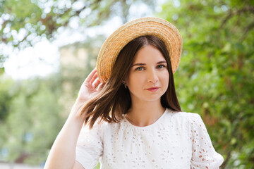 young woman in a straw hat smiles in the summer in nature. Summer holidays
