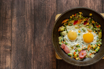 Brunch-fried eggs with vegetables in a frying pan