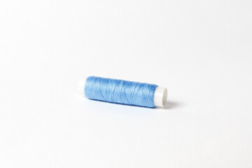 A small bobbin with blue threads on a white background