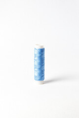 A small bobbin with blue threads on a white background