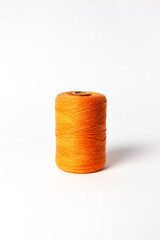 A spool of orange thread. White background.