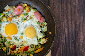 Brunch-fried eggs with vegetables in a frying pan