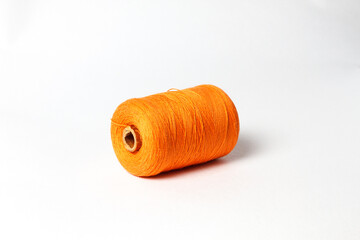 A spool of orange thread. White background.