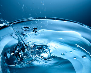 Copo cheio de água  com splash em close em ton azul