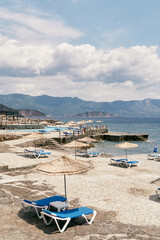 Fototapeta na wymiar Cobbled beach with sun loungers and parasols