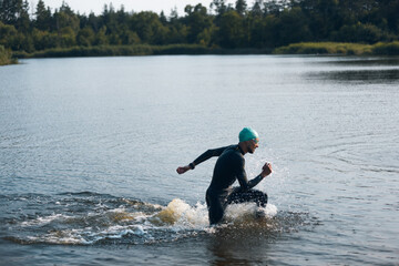 Professional triathlete swimming in river's open water. Man wearing swim equipment practicing...