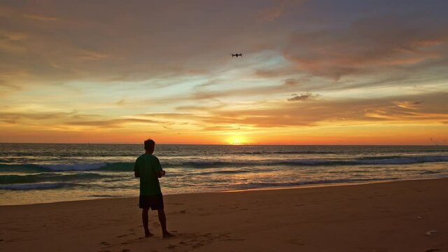 stunning colorful clouds in yellow sky at sunset..A man flying drone in stunning colorful yellow sky at sunset..Tourists piloting drones to take pictures of beautiful sunset.