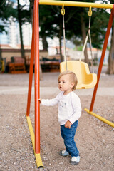 Kid holds the swing with his hand