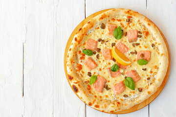Pizza with baked salmon on wooden table