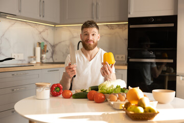 Worried man sit at table and hold pepper and knife