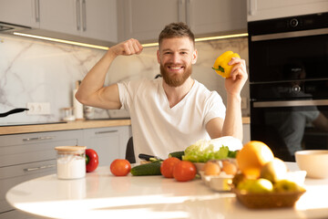 Man showing biceps muscles and peppers at table