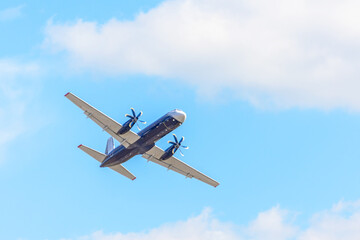 An airplane with propellers on its wings flies in the sky.