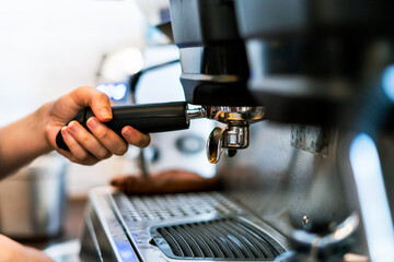Fototapeta na wymiar Close-up hand of barista plug the portafilter into coffee machine to make espresso