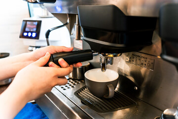Close-up hand of barista plug the portafilter into coffee machine to make espresso