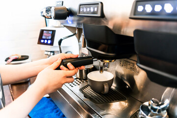 Close-up hand of barista plug the portafilter into coffee machine to make espresso