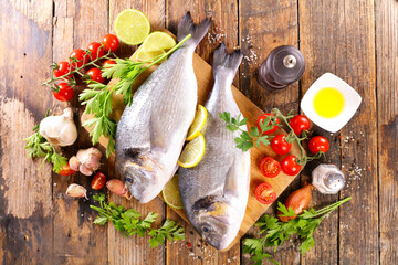 raw fish won wooden board with ingredients and spices