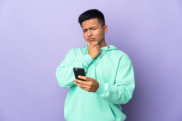 Young Ecuadorian man isolated on purple background thinking and sending a message