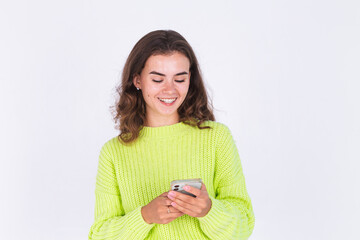 Young beautiful woman with freckles light makeup in sweater on white background with mobile phone texting smile happy