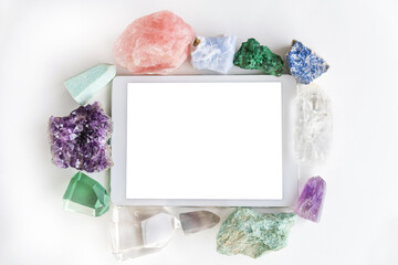 White touchpad with blank touchscreen framed by crystals and gemstones on a white background with...