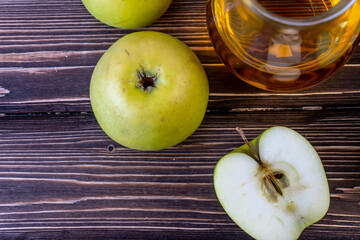 Green apples and jug with apple juice on wooden background