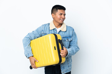 Young Ecuadorian man isolated on white background in vacation with travel suitcase
