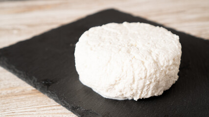 Cottage cheese on a black plate. Fresh cottage cheese in a bowl. Ricotta cheese isolated.