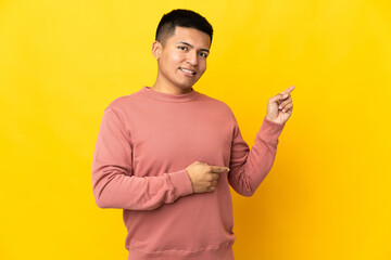 Young Ecuadorian man isolated on yellow background pointing finger to the side