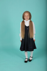 a beautiful little smiling blonde girl in a white shirt and a gray sundress is a schoolgirl