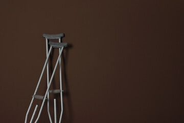 Pair of axillary crutches on brown background. Space for text