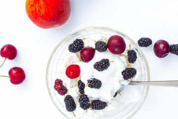 Summer food. A bowl with cottage cheese and ripe juicy cherries and mulberries, coconut cream. A healthy tasty dessert.