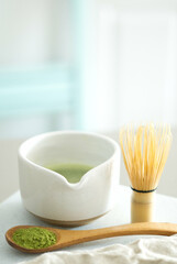 Mixing matcha with wooden spoon and chasen whisk in chawan bowl.