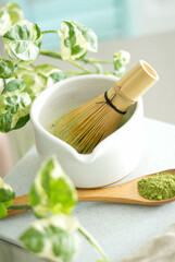 Mixing matcha with wooden spoon and chasen whisk in chawan bowl.