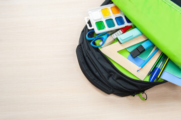 The Student backpack with different stationery on light background, flat lay with space for text. Back to school