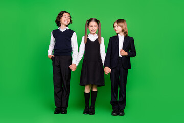 Full size photo of nice little girl boys hold hands look wear school uniform isolated on green background
