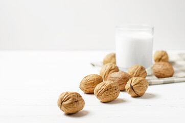 Milk from walnuts and nuts on a white wooden background. Products containing vegetable protein, vitamins, and useful amino acids. Copy space.