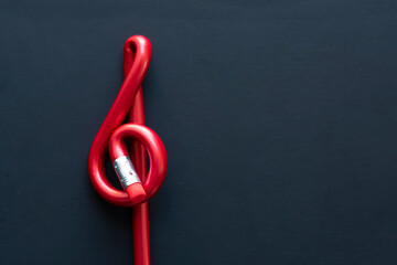 Red pen with treble clef form on black background