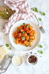 Traditional Italian potato gnocchi with tomato sauce, parmesan cheese and fresh basil. Top view.