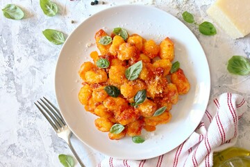 Traditional Italian potato gnocchi with tomato sauce, parmesan cheese and fresh basil. Top view.
