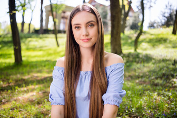 Fototapeta premium Portrait of attractive peaceful girl sitting on fresh air green grass resting at downtown outdoors