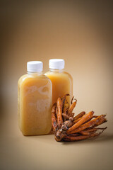 Kaempferia extract in bottle and fresh galangal on brown background.