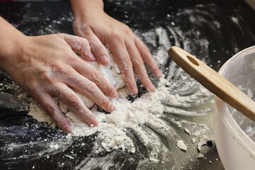 Close up view of woman's hands mixing dough on a table at home