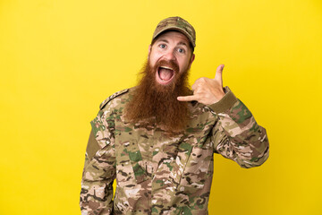 Military Redhead man over isolated on yellow background making phone gesture. Call me back sign