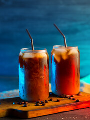 cold brew cold coffee in tall glasses with cream and roasted coffee beans. neon style backlight background