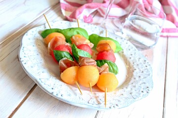 Healthy snack melon, watermelon, raw ham and basil on white background. Healthy food. Top view.