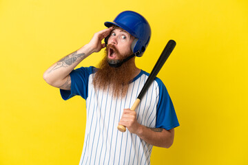 Redhead baseball player man with helmet and bat isolated on yellow background doing surprise gesture while looking to the side