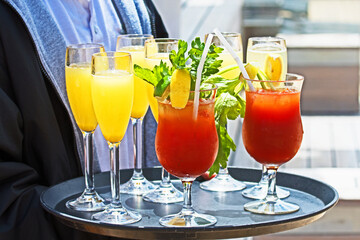 A waiter carries a tray of fresh, delicious summer cocktails.