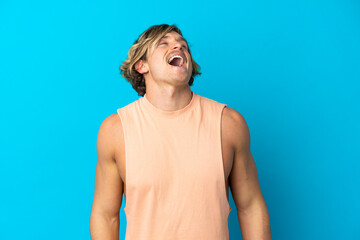 Handsome blonde man isolated on blue background laughing